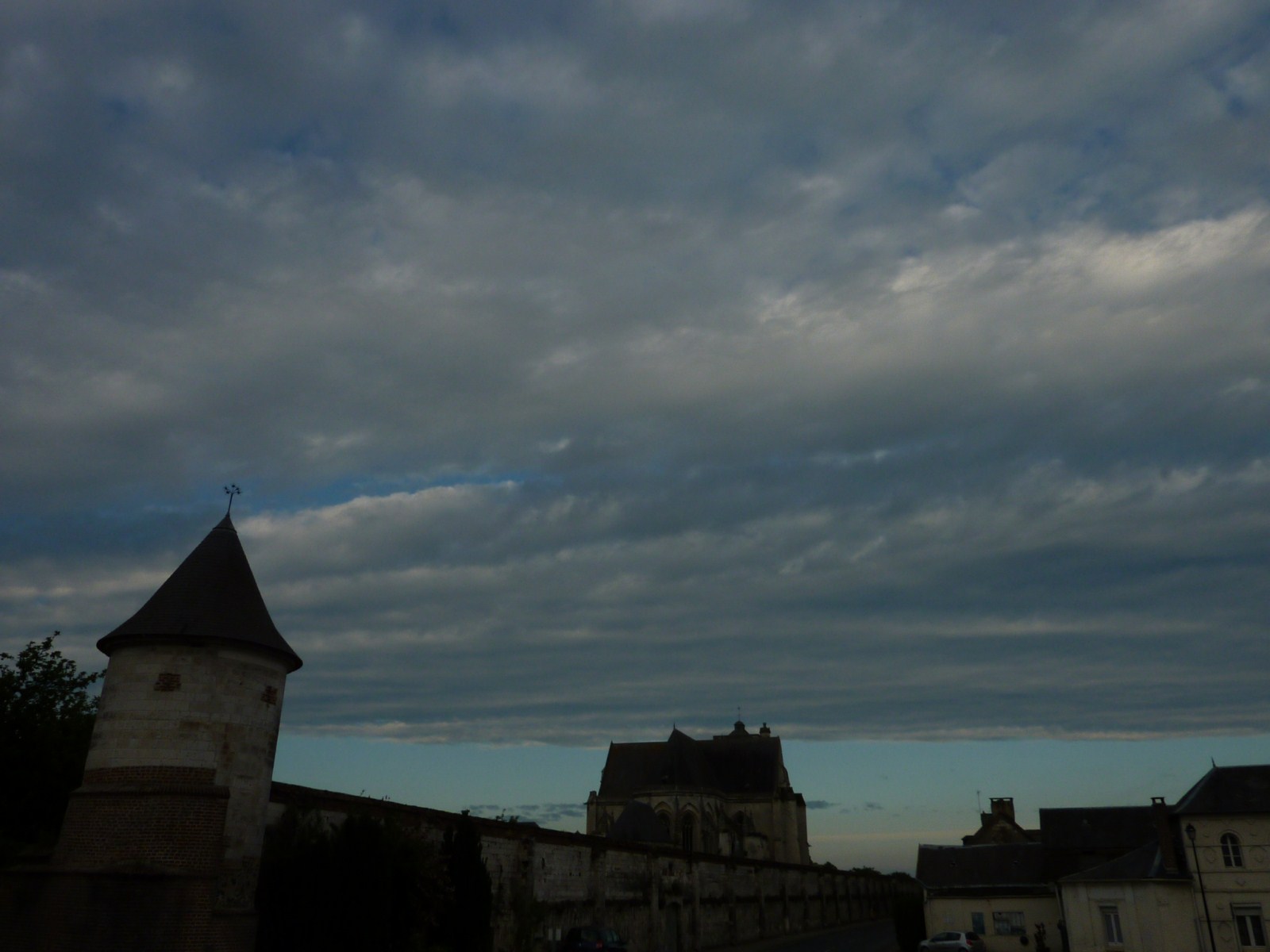 Altostratus couvrant le ciel d'un village. Ils sont de couleur grise.