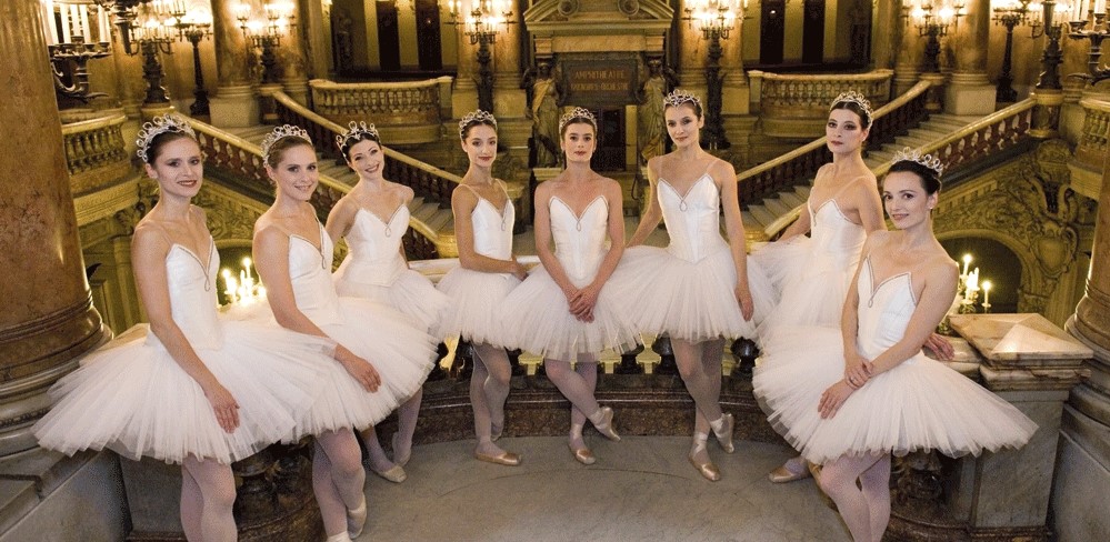 Photo de 8 Etoiles de l'Opéra de Paris de 2013. Les danseuses sont en tutu blanc, pointes aux pieds. Elles se trouvent sur le balcon à l'étage dans l'entrée de L'Opéra