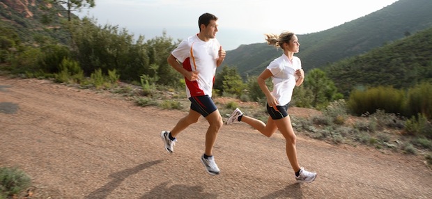 Deux coureurs, un homme et une femme, courent sur une route en montagne.